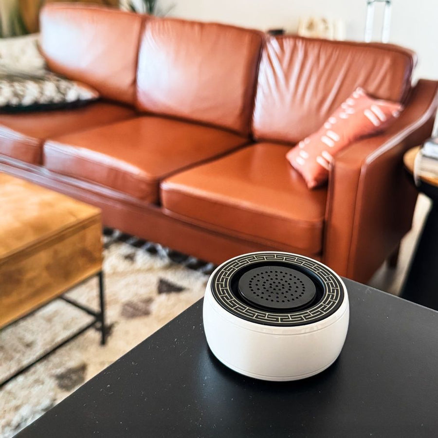 White SIBŌ sound bath device on a black table in front of a leather sofa
