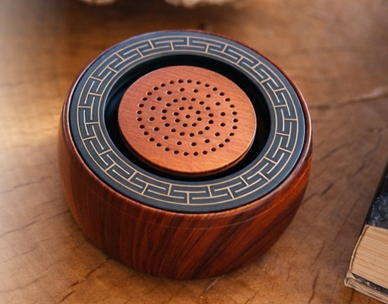 Close-up of the TŌNEM speaker grille and patterned trim on a wooden surface
