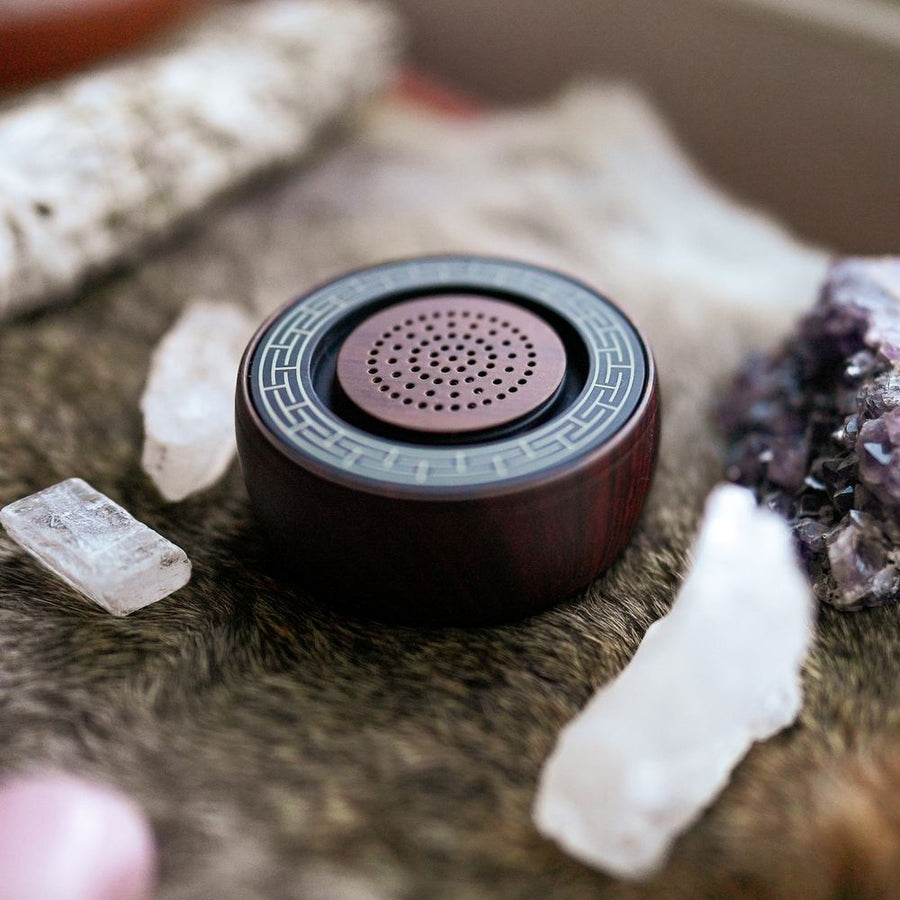 TŌNEM speaker on a fur throw surrounded by quartz and amethyst crystals
