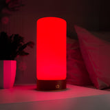 RŪBI 670nm red light lamp glowing on a white bedside table next to a bed