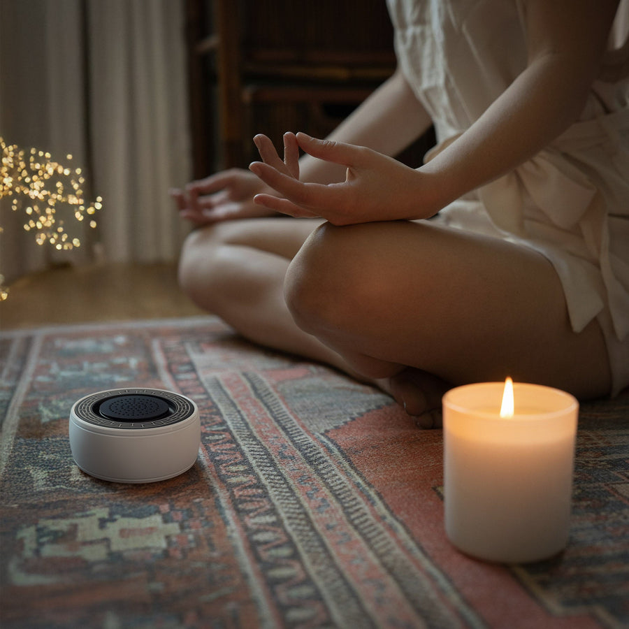 Person meditating on a rug next to SIBŌ and a candle