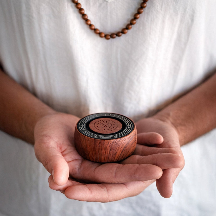 Hands holding the palm-sized TŌNEM speaker