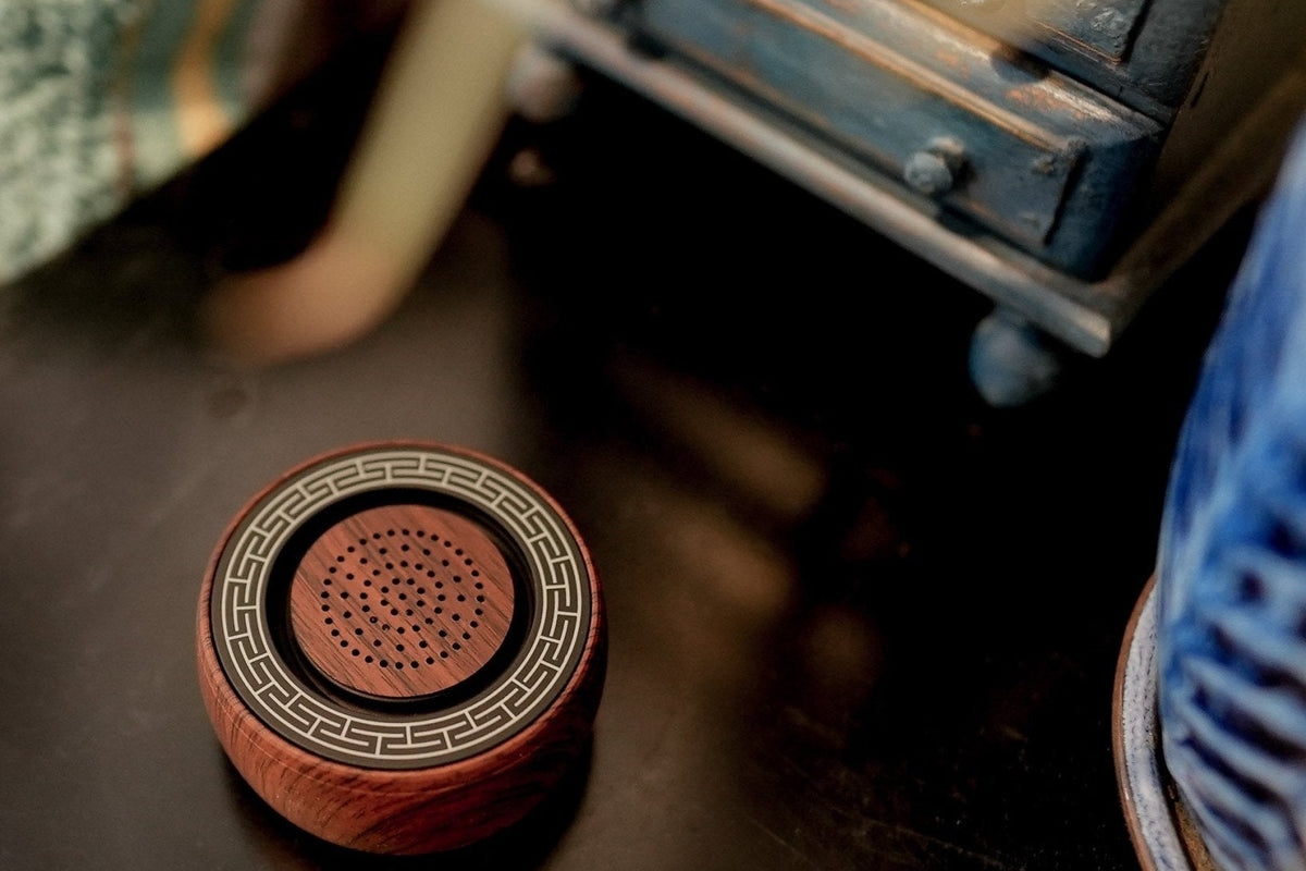 TŌNEM sound therapy speaker on a dark nightstand in front of a blue dresser